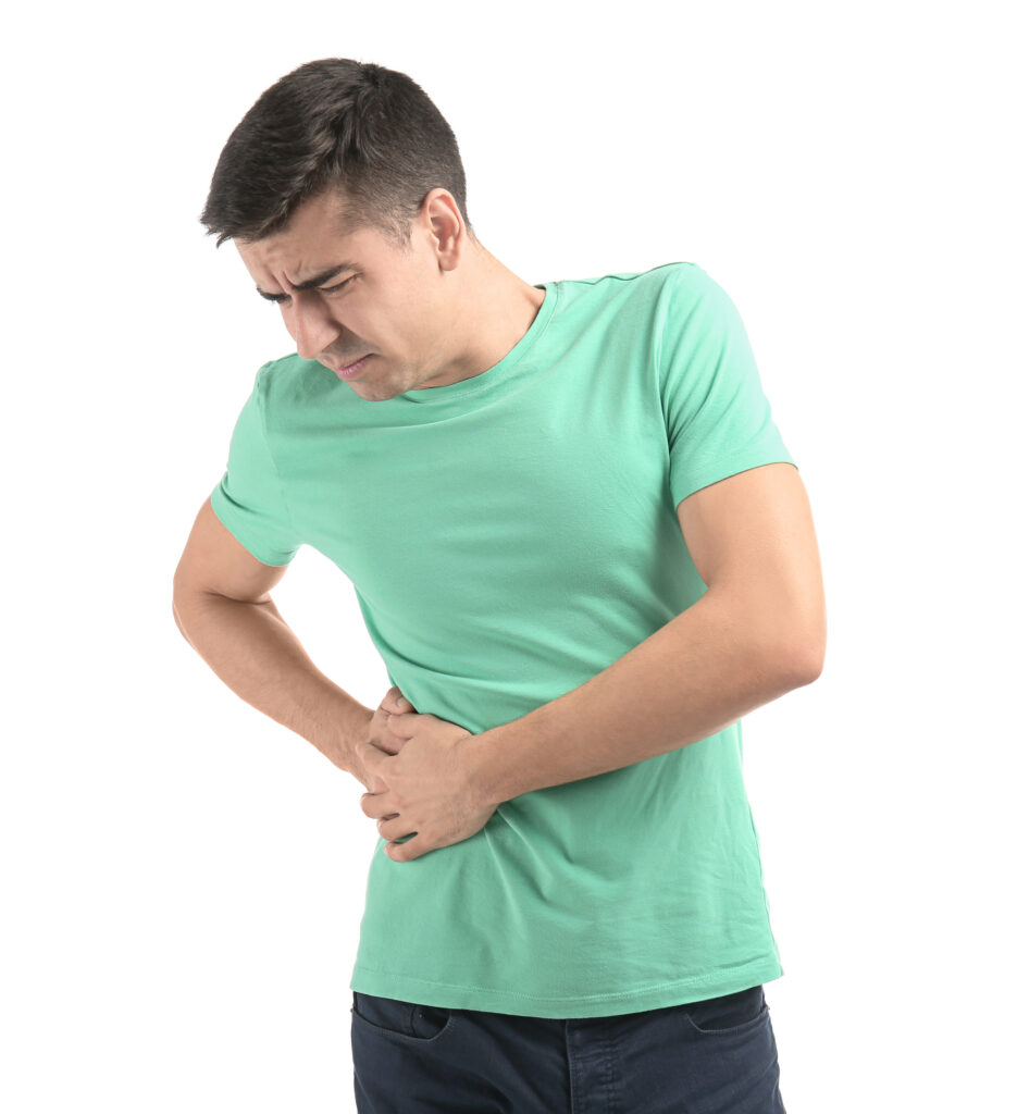A man in a mint green t-shirt holds his right side and winces in pain, suggesting discomfort or possible bladder leaks, against a plain white background.